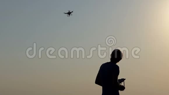 聪明的人在太阳落山时用面板控制他的飞行无人机视频的预览图