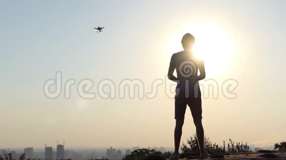 阳光明媚的人在日落时分用面板控制着他的旋转无人机视频的预览图