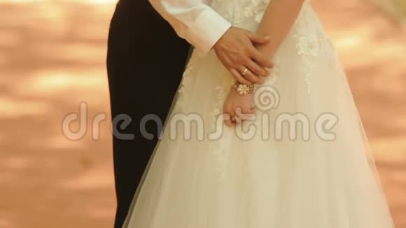 新郎温柔地抚摸着新娘的手臂握住她的手没有脸不知名的新婚夫妇视频的预览图