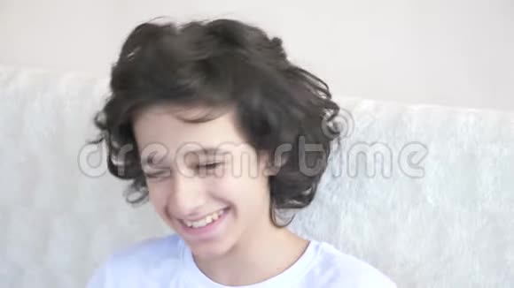 可爱的卷发男孩少年看着镜头笑做出一个有趣的面部表情4k慢动作视频的预览图