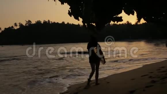 日落时带冲浪板的女孩视频的预览图