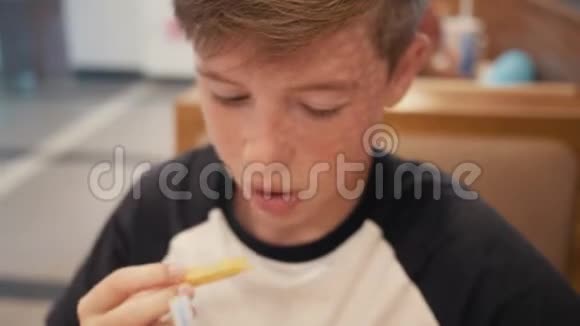 一个在快餐店的男孩在快餐店吃汉堡和炸薯条有害营养视频的预览图