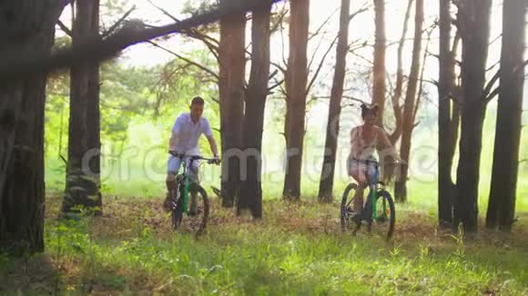 快乐的一对夫妇在松林的小路上骑自行车视频的预览图