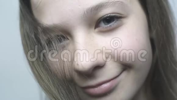 特写一个年轻女孩的肖像看着相机在慢镜头里微笑视频的预览图