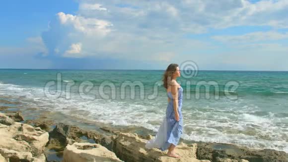 美丽的黑发女人在海边欣赏美丽的景色天空阴云密布视频的预览图