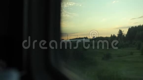 一列火车去乡下从窗口查看日落时乘火车旅行绿草和树木的景观视频的预览图