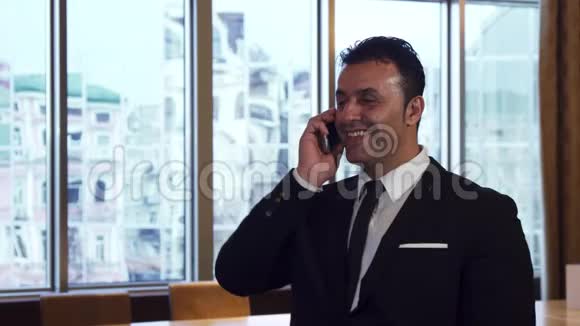 一个快乐的男人正在办公室里用手机说话视频的预览图