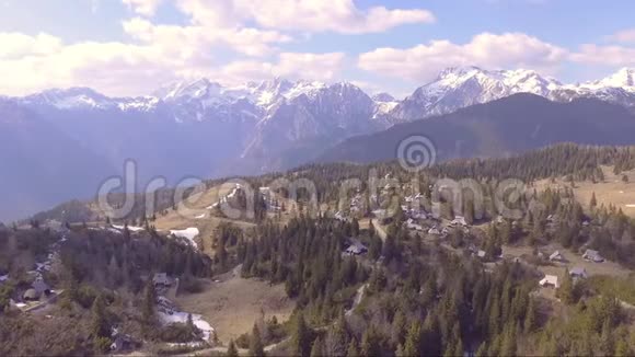 飞越美丽的维利卡平原充满云杉小房子和山脉在后面空中摄影机拍摄视频的预览图
