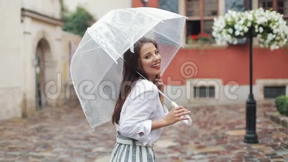 快乐的年轻女子在老城的街道上用雨伞跳舞和玩漂亮的卷发造型视频的预览图