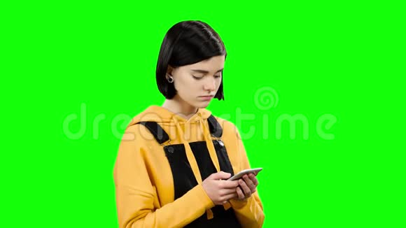 女孩看着手机看到奇怪的照片绿色屏幕视频的预览图