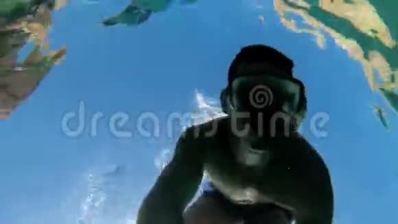 戴着浮潜面具的年轻人潜入红海清澈的海水中视频的预览图