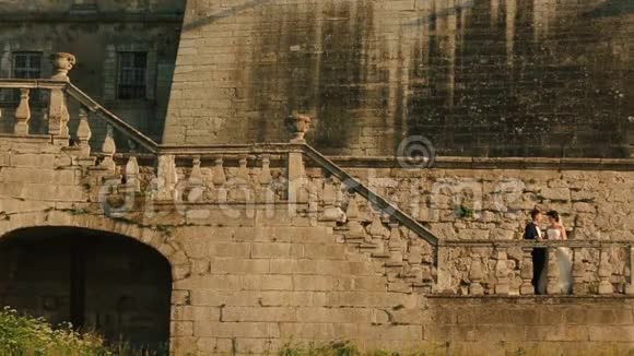 华丽的新婚夫妇在古堡的楼梯上接吻视频的预览图