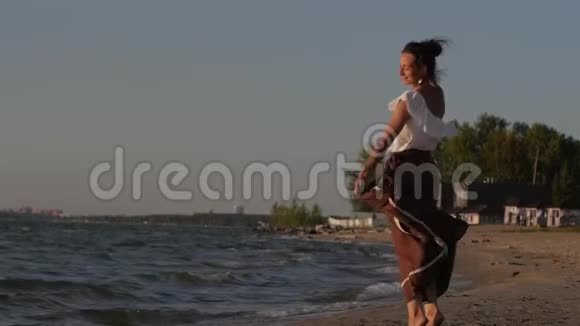 女人在夕阳大海的背景下跳舞沿着海滩散步的女人视频的预览图