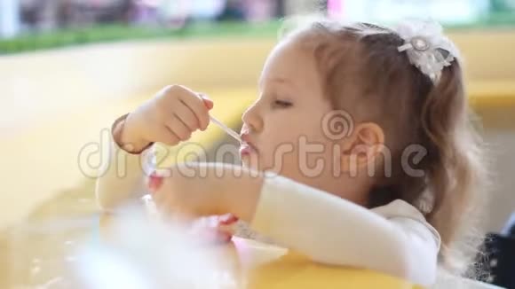 小女孩在咖啡馆里吃甜点吃冰淇淋的婴儿的肖像特写视频的预览图