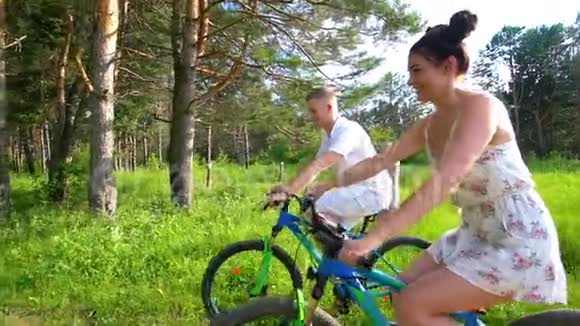 有魅力的年轻夫妇在夏天的森林里骑自行车视频的预览图