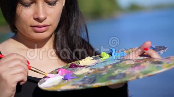 夏天户外一位美丽的40岁黑发女子艺术家的肖像用颜料特写调色板视频的预览图