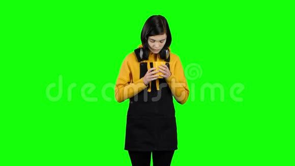 穿连衣裙的女孩喝黄色玻璃茶绿色屏幕视频的预览图