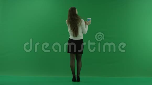女孩站在镜头前从绿色屏幕上的玻璃杯里喝着酒视频的预览图