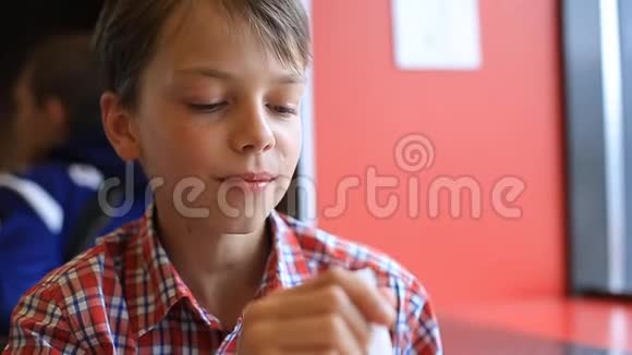 一个男孩正在咖啡馆里吃冰淇淋咖啡馆里那个金发男孩正在用勺子吃冰淇淋视频的预览图