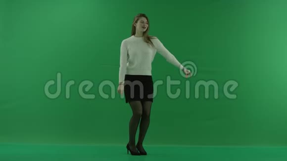 女孩站在一个半转弯看着右边在绿色的屏幕上跳舞视频的预览图