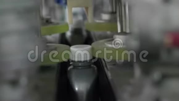 自动装置关闭发动机油厂生产线上灰色塑料瓶上的盖子视频的预览图