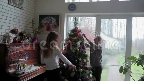 两个女孩在窗边装饰圣诞树视频的预览图