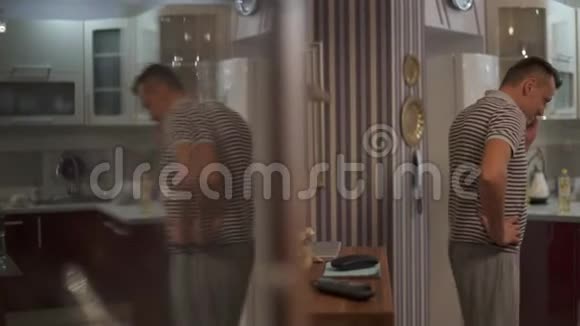 厨房里的一个男人用手机说话走在厨房里紧张地解决问题视频的预览图