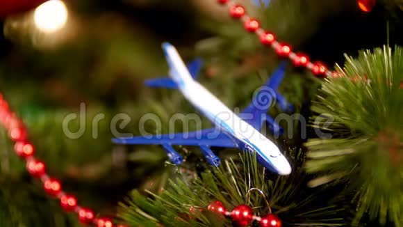 特写4k视频的微型飞机躺在圣诞树上发光的彩色灯光旅行的概念视频的预览图