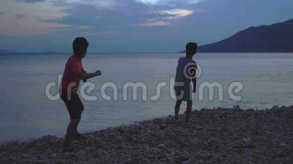 两个男孩日落时在海上跳过石头视频的预览图