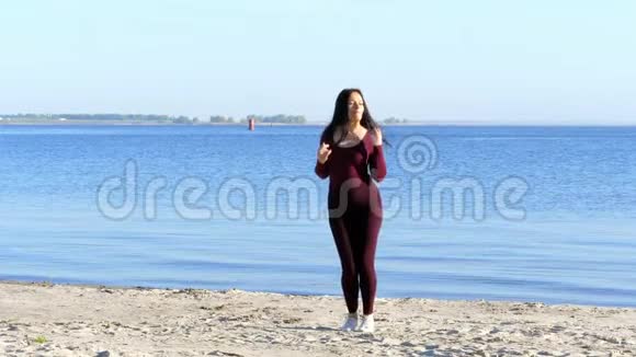 夏天河岸上沙滩上黎明时一位美丽的女艺术家穿着紧身西装跳舞跳跃视频的预览图