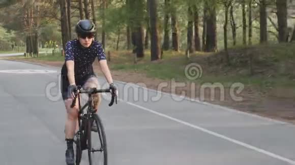 骑着黑色自行车的女孩穿着蓝色球衣和黑色头盔在公园里骑马自行车比赛的训练视频的预览图