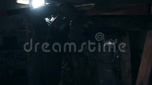 在机械库的一个旧汽车结构上焊接东西的工人视频的预览图