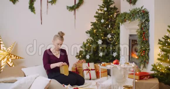 妇女在家中用壁炉包装圣诞礼物视频的预览图
