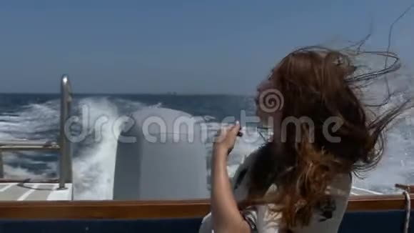 年轻女子把头发整理好坐在一艘移动的摩托艇上视频的预览图