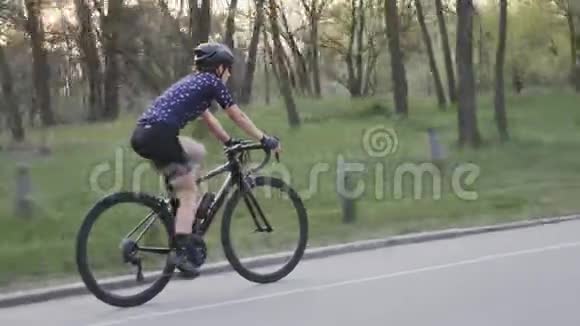 穿蓝色运动衫戴黑色头盔的女孩在公园里骑自行车公路自行车训练自行车概念视频的预览图