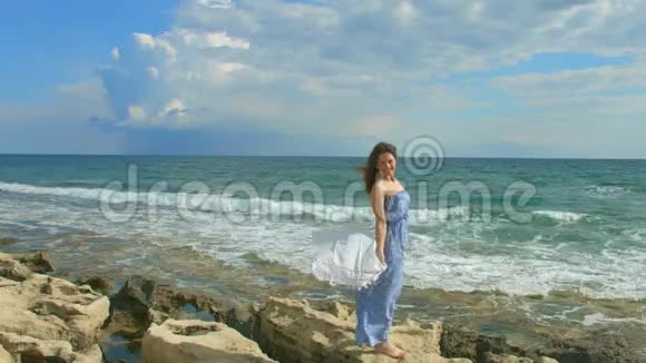 美丽的黑发女人穿着马西连衣裙在海滨享受风日度假视频的预览图