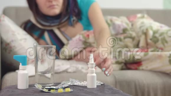 桌子椅子上的喷雾和水年轻的生病的女孩采取治疗鼻涕的背景视频的预览图