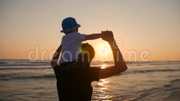 母亲和小儿子在日落时在海滩上散步和玩耍视频的预览图