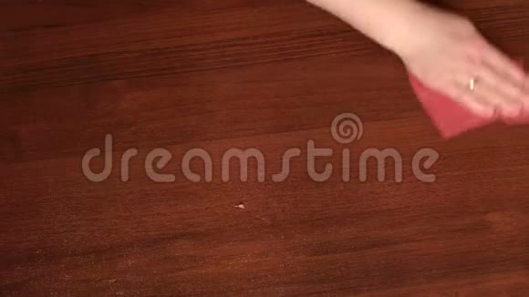 一个女人用粉色抹布擦拭桌子的特写镜头视频的预览图