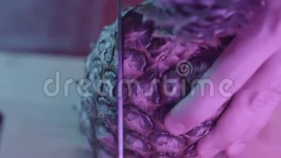 深色背景下的切熟菠萝特写行动凤梨在霓虹灯下的刀切视频的预览图