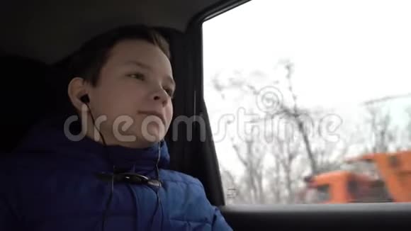 小男孩坐在车后座听耳机里的音乐视频的预览图