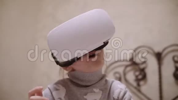 小女孩在VR耳机上抬头试图触摸虚拟现实中的物体在家里室内视频的预览图