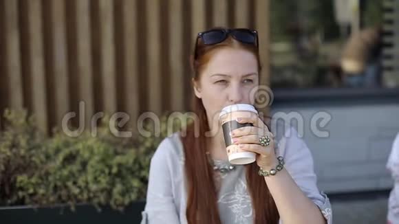 美丽的白种人年轻女子晚上下班后坐在街边的咖啡馆里喝着咖啡聊着天视频的预览图