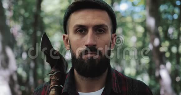 严肃自信的伐木工人的肖像成年胡须男拿着一把大斧头在户外看着镜头视频的预览图