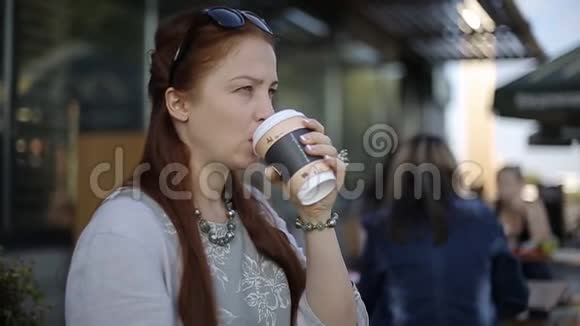 美丽的白种人年轻女子晚上下班后坐在街边的咖啡馆里喝着咖啡聊着天视频的预览图