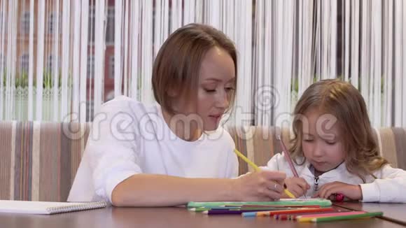 年轻积极可爱的妈妈和她漂亮的小女儿一起画画视频的预览图