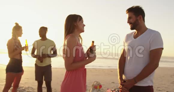 日落时分在海滩上喝酒的年轻成年朋友视频的预览图
