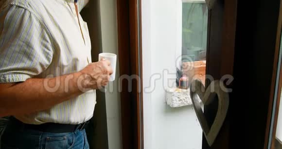 在家喝咖啡时老人透过窗户看着视频的预览图