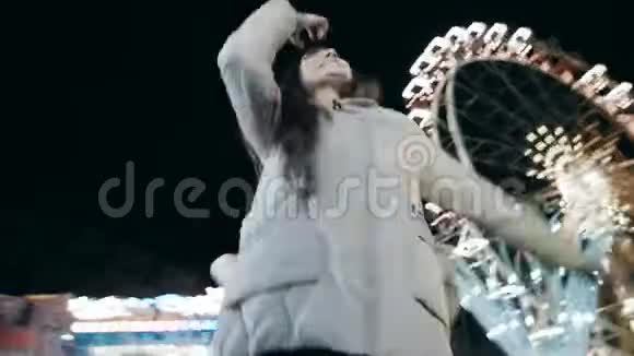两位美丽的年轻女子晚上在游乐园中跳舞时镜头的循环移动视频的预览图