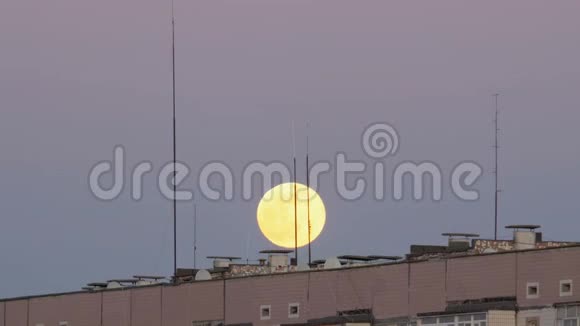 一栋多层建筑屋顶上方的满月正在上升视频的预览图